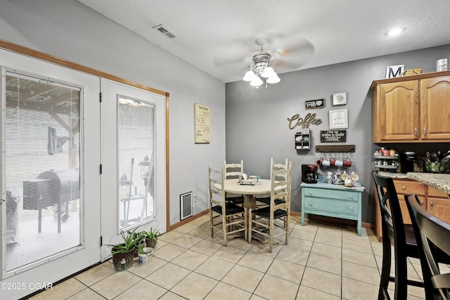 tiled dining area with a textured ceiling and ceiling fan