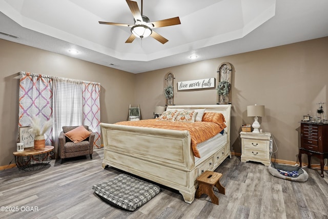 bedroom featuring hardwood / wood-style floors, ceiling fan, and a tray ceiling