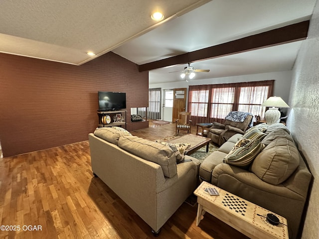 living room featuring beam ceiling, ceiling fan, hardwood / wood-style flooring, and a textured ceiling