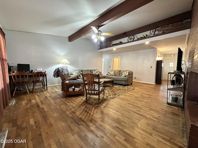 living room with hardwood / wood-style flooring, ceiling fan, and beam ceiling