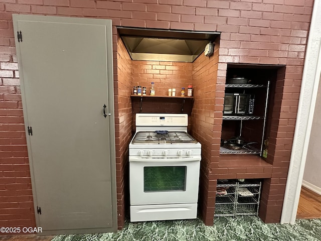 kitchen featuring gas range gas stove and brick wall