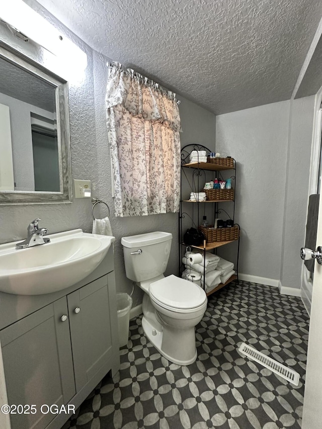 bathroom featuring vanity, toilet, and a textured ceiling