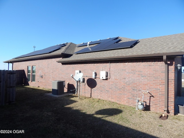 view of side of home with a yard, central AC unit, and solar panels