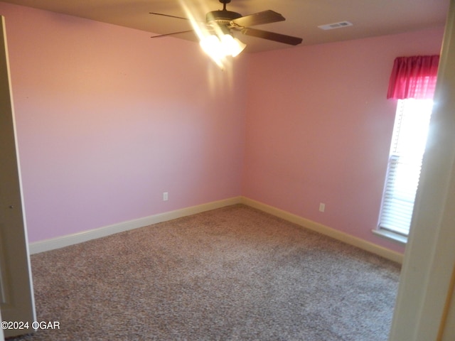 spare room with a wealth of natural light, ceiling fan, and carpet