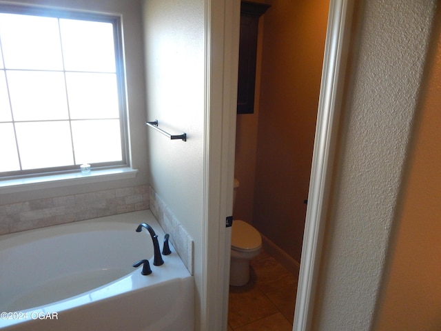 bathroom featuring tile patterned flooring, a tub, and toilet