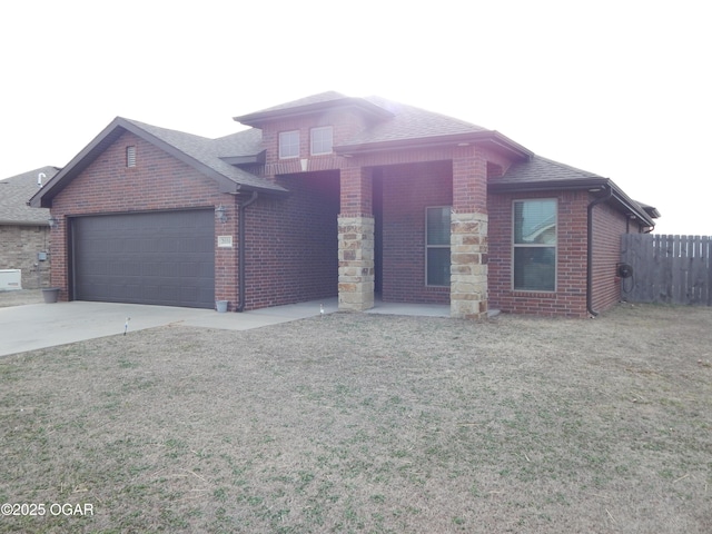 view of front of home with brick siding, roof with shingles, an attached garage, driveway, and a front lawn