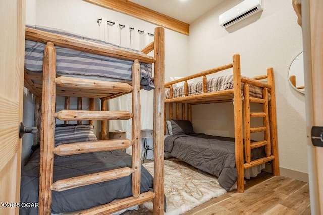 bedroom featuring light wood-type flooring and an AC wall unit