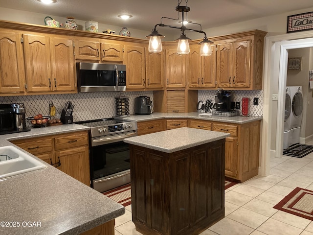 kitchen featuring decorative light fixtures, stainless steel appliances, washing machine and dryer, and light tile patterned flooring