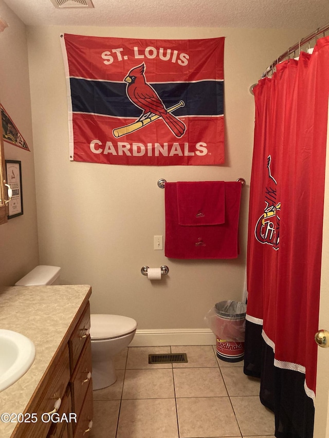 bathroom featuring vanity, toilet, tile patterned flooring, and a textured ceiling