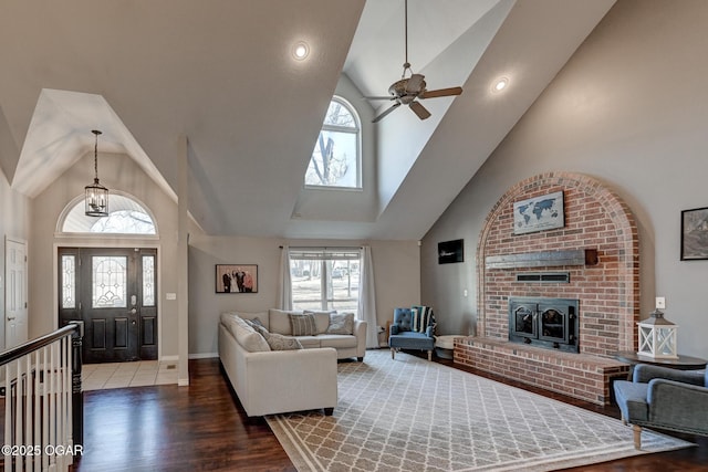 living room with hardwood / wood-style flooring, ceiling fan, high vaulted ceiling, and a fireplace