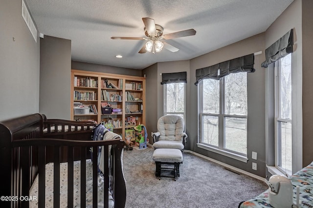 carpeted bedroom with ceiling fan and a textured ceiling