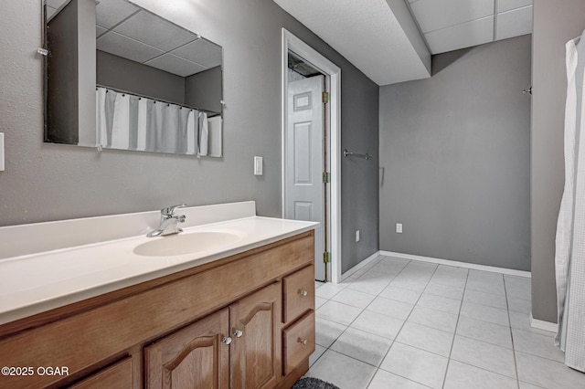 bathroom featuring tile patterned floors, vanity, and a drop ceiling