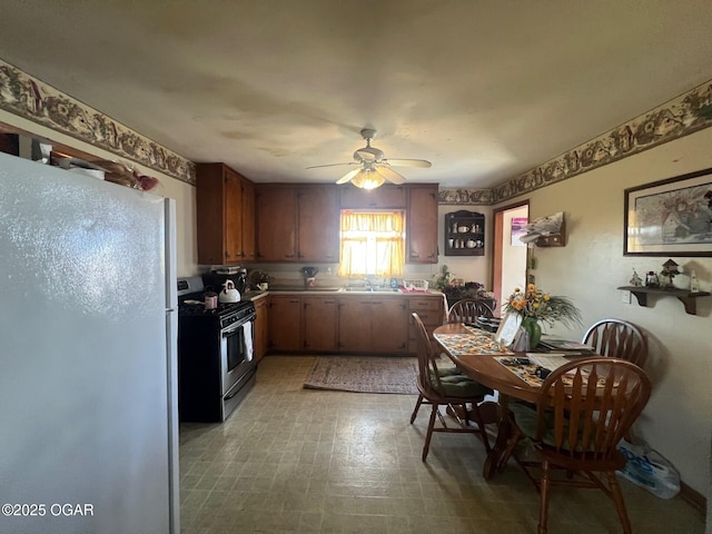 kitchen featuring white refrigerator, sink, stainless steel gas range, and ceiling fan