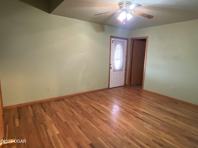 interior space with a ceiling fan, baseboards, and wood finished floors