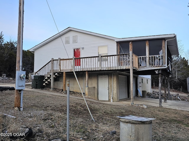 rear view of house with a garage, a sunroom, and a deck