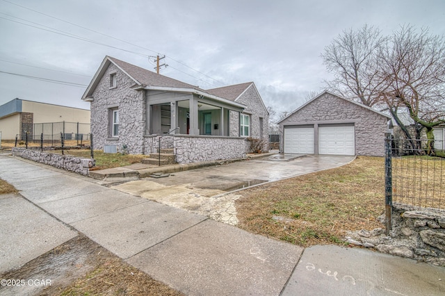 view of front of home with a garage, an outbuilding, stone siding, and fence