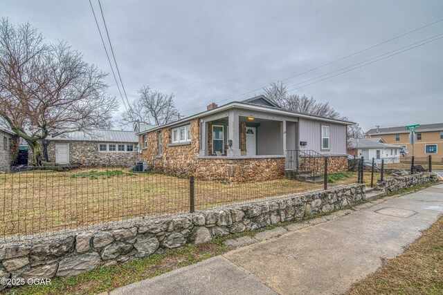 615 E 15th St, Joplin, MO 64801 - view of front of house featuring stone siding, a chimney, covered porch, fence, and a front lawn