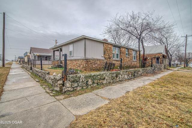 615 E 15th St, Joplin, MO 64801 - view of side of home with stone siding, a fenced front yard, and a lawn