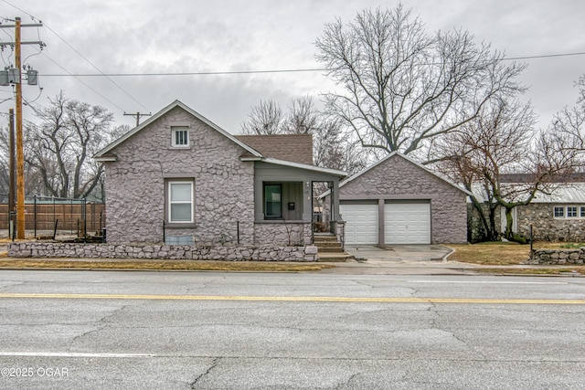 view of front facade with a porch, stone siding, a shingled roof, and fence