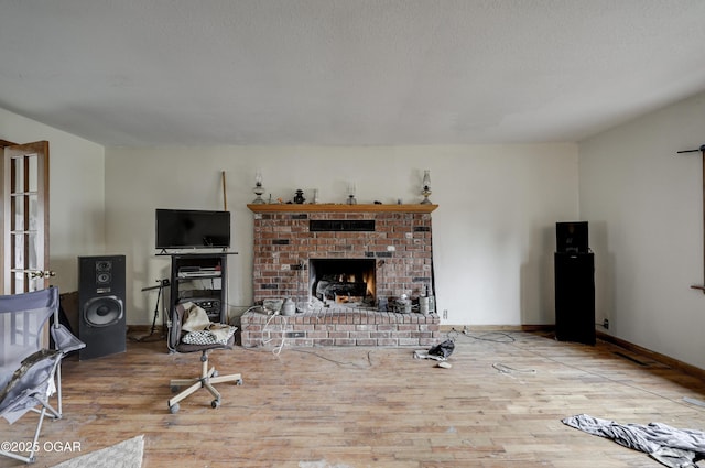 living room featuring a textured ceiling, a brick fireplace, and light wood-type flooring