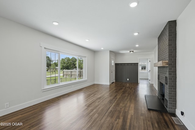 540 E 4th St, Baxter Springs, KS 66713 - unfurnished living room featuring a brick fireplace, dark wood-style floors, baseboards, and recessed lighting