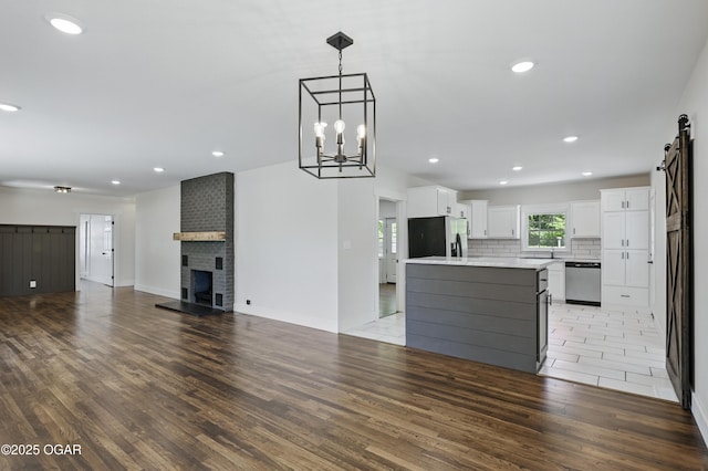 540 E 4th St, Baxter Springs, KS 66713 - kitchen with stainless steel appliances, white cabinets, open floor plan, light wood-style floors, and light countertops