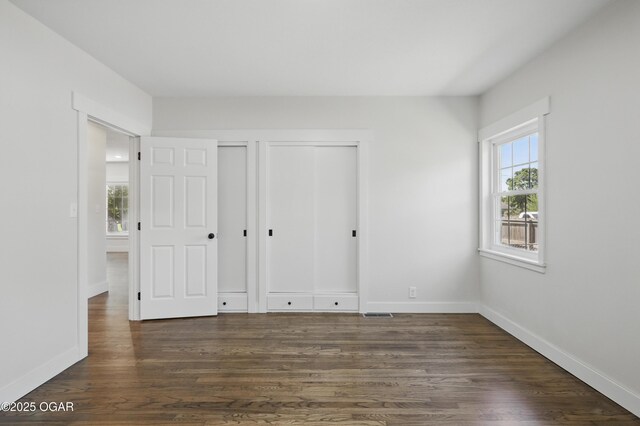 540 E 4th St, Baxter Springs, KS 66713 - unfurnished bedroom with dark wood-style flooring, multiple closets, and baseboards