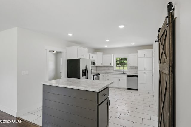 540 E 4th St, Baxter Springs, KS 66713 - kitchen featuring appliances with stainless steel finishes, a barn door, white cabinetry, light countertops, and recessed lighting