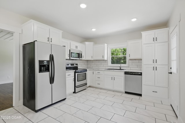 540 E 4th St, Baxter Springs, KS 66713 - kitchen featuring stainless steel appliances, a sink, white cabinetry, decorative backsplash, and light countertops
