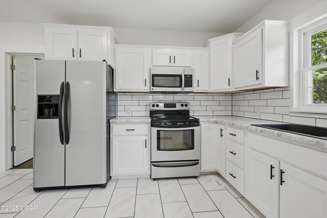 540 E 4th St, Baxter Springs, KS 66713 - kitchen with stainless steel appliances, white cabinets, decorative backsplash, and light stone counters