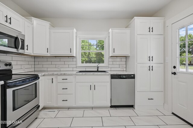 540 E 4th St, Baxter Springs, KS 66713 - kitchen featuring appliances with stainless steel finishes, a sink, white cabinets, and decorative backsplash