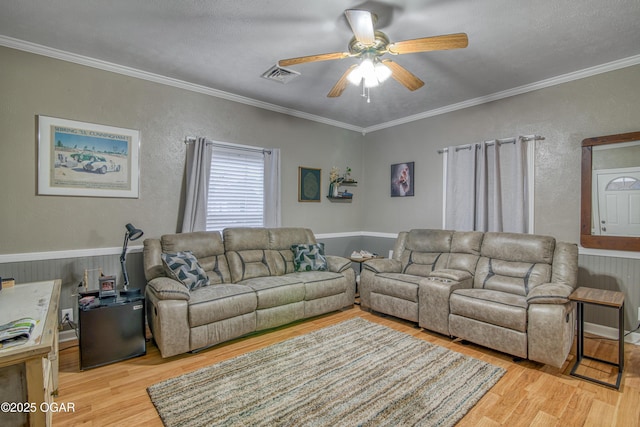 living room featuring ornamental molding, light hardwood / wood-style floors, and ceiling fan