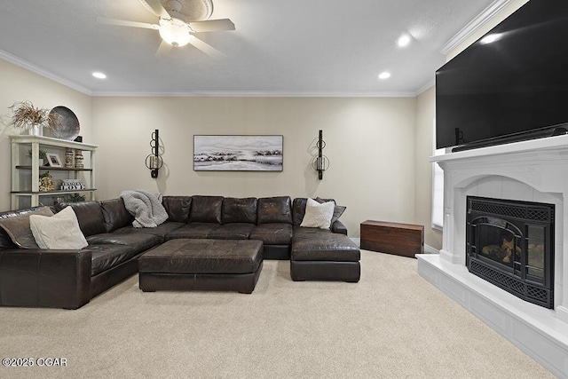 carpeted living room with crown molding, ceiling fan, and a tiled fireplace