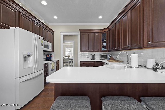 kitchen with white appliances, kitchen peninsula, sink, and backsplash