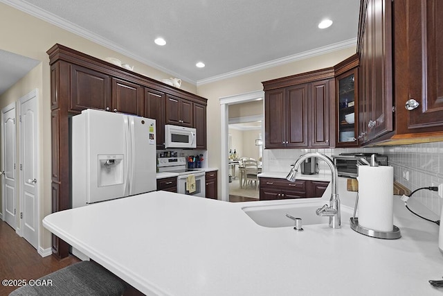 kitchen featuring crown molding, sink, backsplash, and white appliances