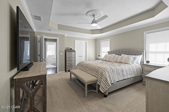 bedroom featuring crown molding, carpet, a raised ceiling, a textured ceiling, and a closet