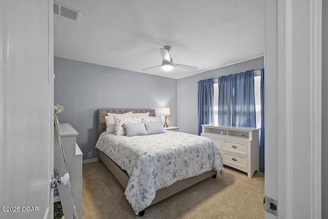 carpeted bedroom featuring ceiling fan and a textured ceiling