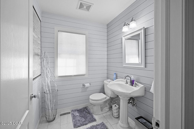 bathroom with sink, wooden walls, and toilet