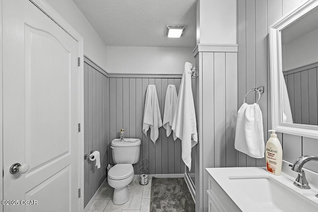 bathroom featuring vanity, toilet, and a textured ceiling