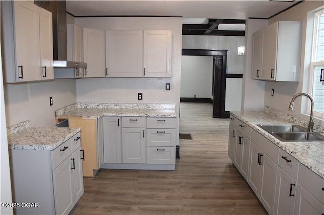 kitchen with white cabinetry, wall chimney exhaust hood, light hardwood / wood-style floors, and sink