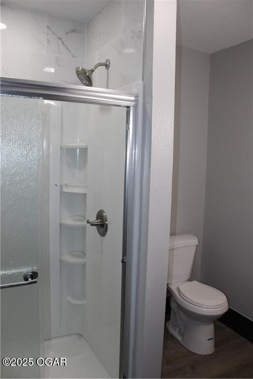 bathroom with hardwood / wood-style flooring, toilet, and an enclosed shower