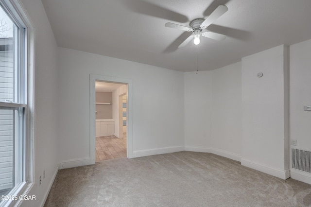 carpeted empty room featuring ceiling fan and plenty of natural light