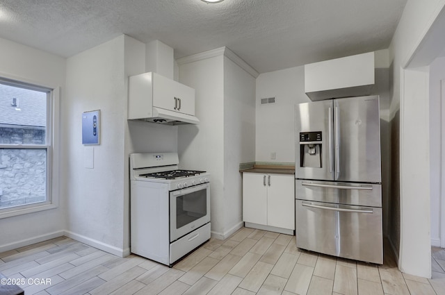 kitchen featuring white gas stove, white cabinets, a textured ceiling, and stainless steel fridge with ice dispenser