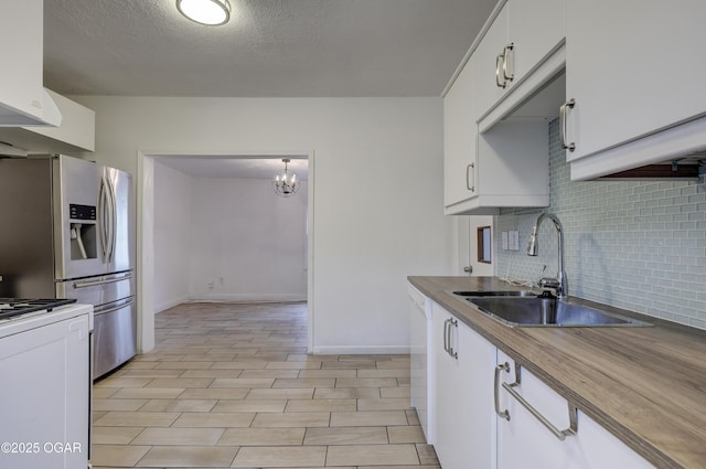 kitchen featuring sink, white cabinets, backsplash, hanging light fixtures, and white appliances