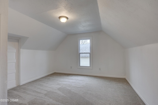 additional living space featuring light colored carpet, lofted ceiling, and a textured ceiling