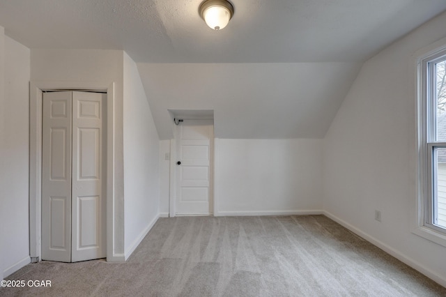 bonus room with lofted ceiling and light carpet