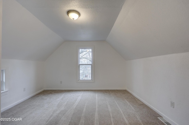 bonus room featuring vaulted ceiling, carpet floors, and a textured ceiling