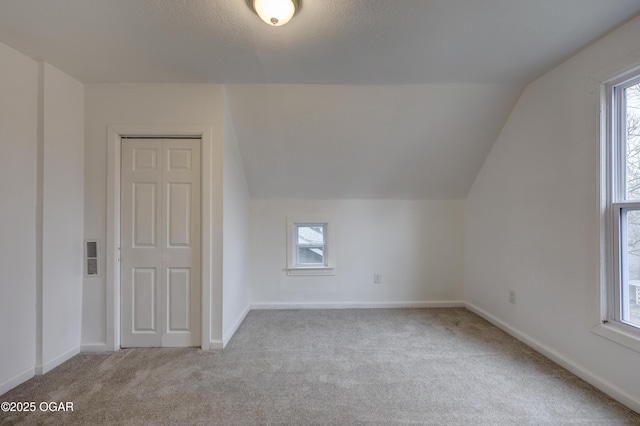 additional living space featuring vaulted ceiling and light colored carpet