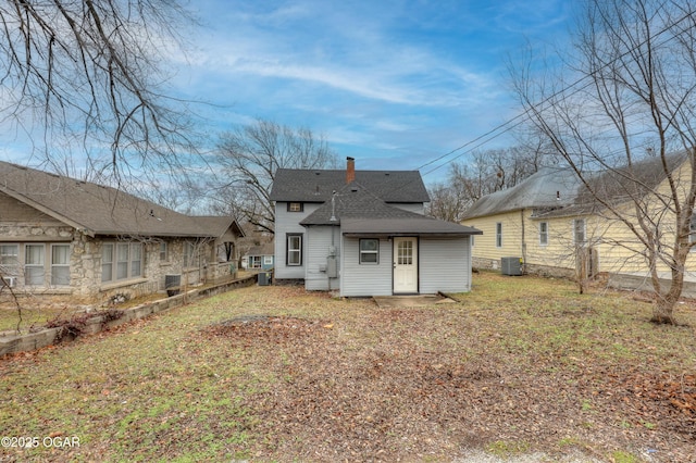 rear view of house with central AC unit and a lawn