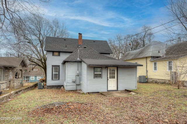 rear view of property featuring central AC unit and a lawn